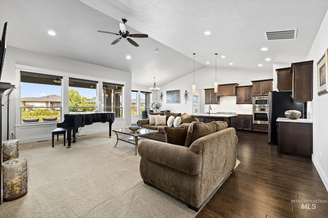 living room featuring ceiling fan with notable chandelier, dark hardwood / wood-style flooring, sink, and vaulted ceiling