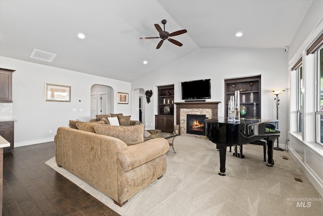 living room with hardwood / wood-style flooring, vaulted ceiling, plenty of natural light, and a stone fireplace