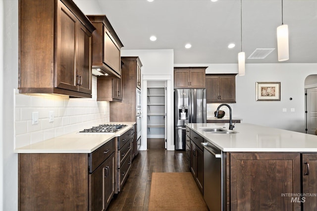 kitchen featuring dark brown cabinets, stainless steel appliances, sink, dark hardwood / wood-style floors, and hanging light fixtures