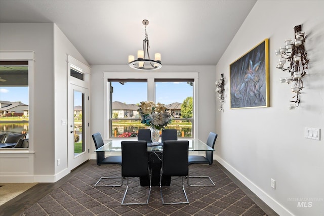 dining area with an inviting chandelier, dark wood-type flooring, and vaulted ceiling