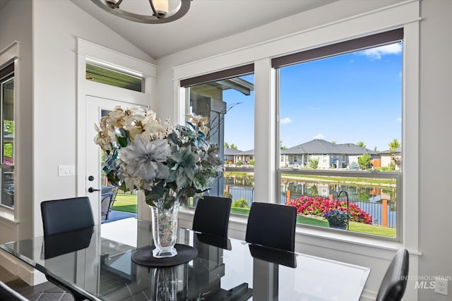 dining area featuring a water view and lofted ceiling