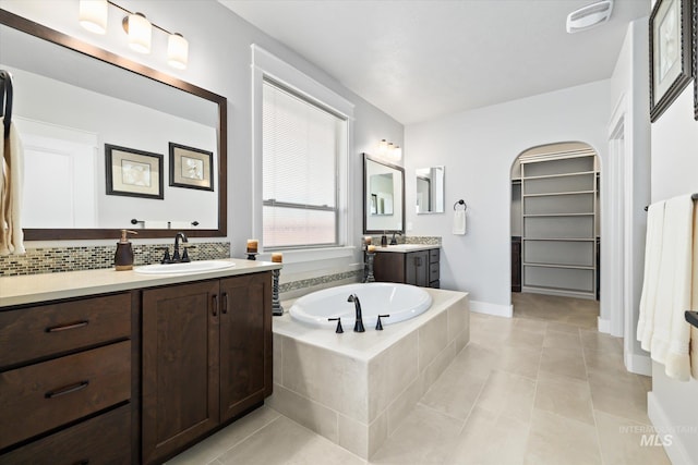 bathroom featuring tile patterned floors, vanity, and a relaxing tiled tub