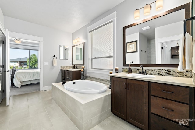 bathroom featuring tile patterned flooring, decorative backsplash, vanity, and a relaxing tiled tub