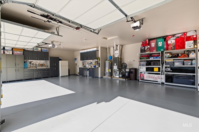 garage featuring white fridge, gas water heater, and a garage door opener