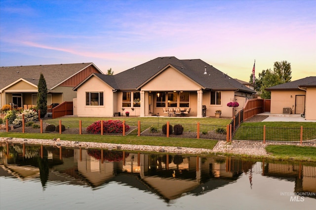 back house at dusk featuring a yard and a water view