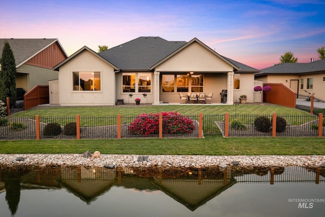 back house at dusk with a yard and a patio area