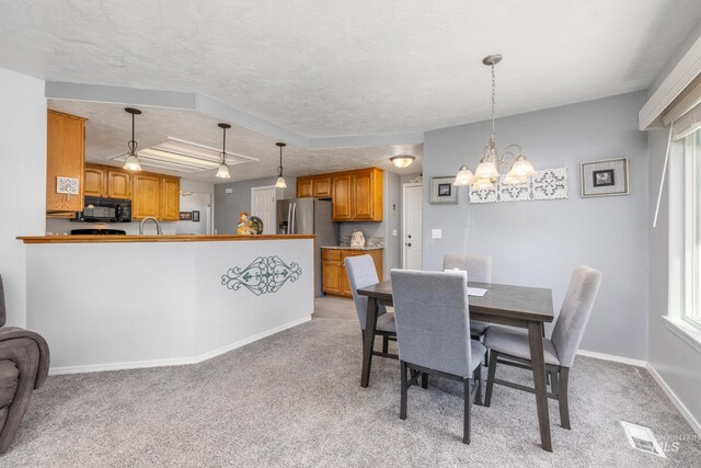 dining room featuring light colored carpet, a chandelier, and baseboards