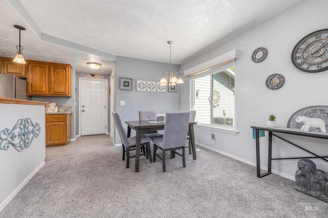 dining area featuring light carpet, a chandelier, baseboards, and a textured ceiling