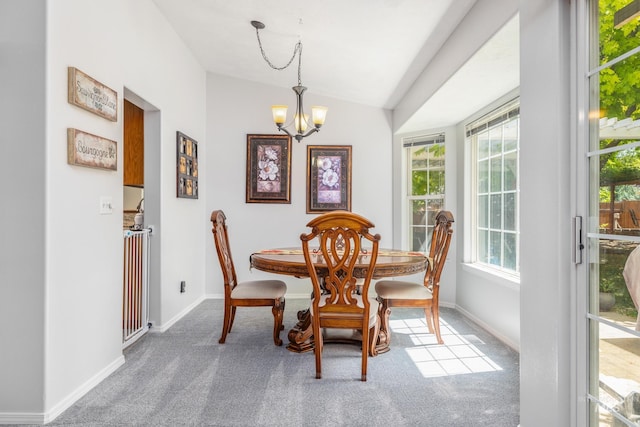dining room featuring a chandelier, plenty of natural light, carpet floors, vaulted ceiling, and baseboards