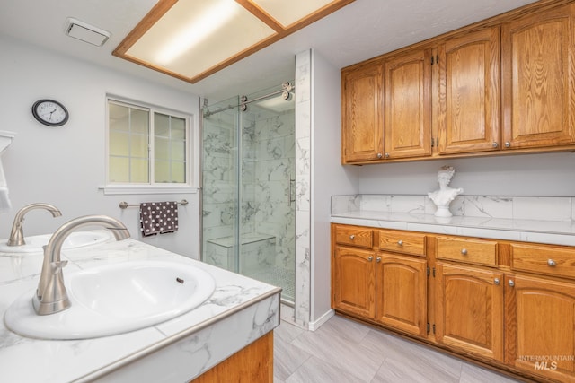 full bathroom with a marble finish shower and vanity