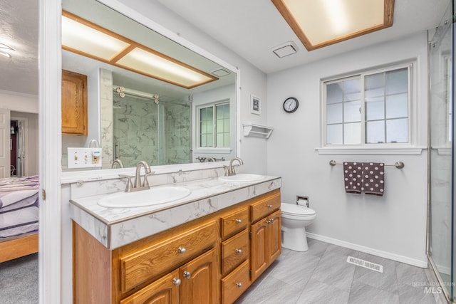 bathroom with a marble finish shower, double vanity, toilet, and baseboards