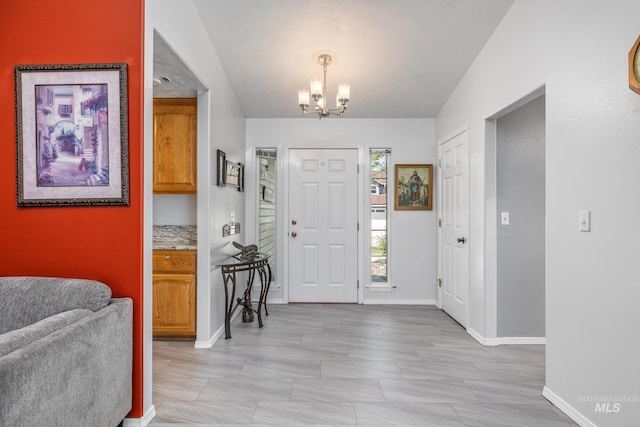 foyer entrance featuring a chandelier and baseboards