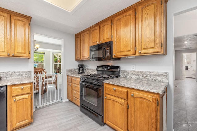 kitchen with black appliances, light stone countertops, and brown cabinets