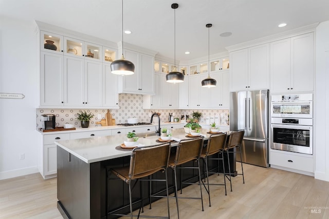 kitchen featuring light countertops, white cabinets, high end refrigerator, a kitchen bar, and tasteful backsplash