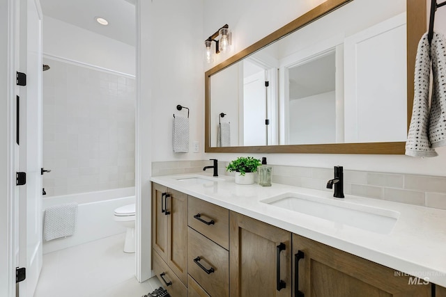 bathroom with a sink, toilet, double vanity, and tile patterned floors