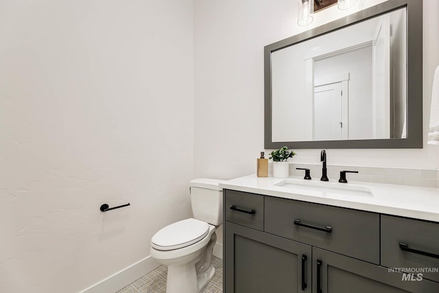 half bathroom featuring toilet, vanity, and baseboards