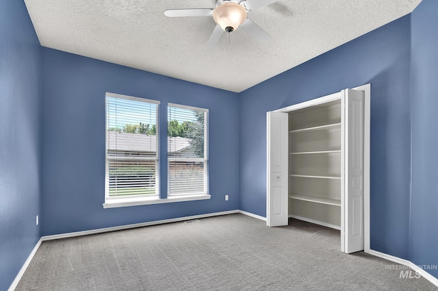 unfurnished bedroom featuring carpet flooring, baseboards, a textured ceiling, and a ceiling fan
