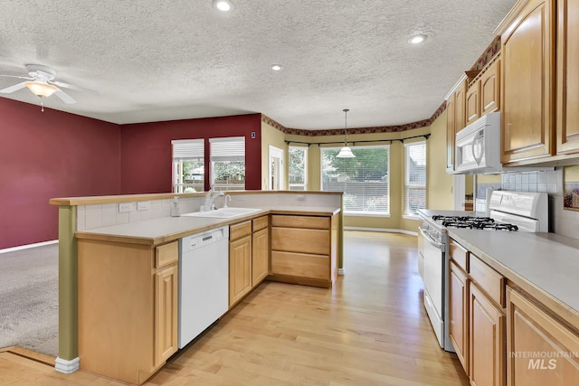 kitchen with white appliances, baseboards, a sink, light countertops, and light wood-style floors