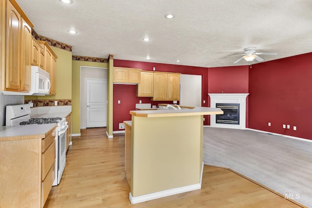 kitchen featuring white appliances, ceiling fan, a center island, baseboards, and a textured ceiling