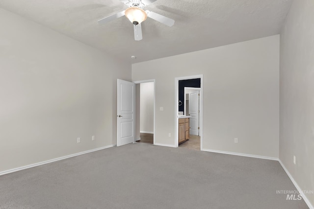 unfurnished bedroom with light colored carpet, baseboards, ensuite bathroom, and a ceiling fan