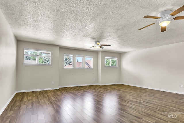 spare room featuring ceiling fan, baseboards, wood finished floors, and a textured ceiling