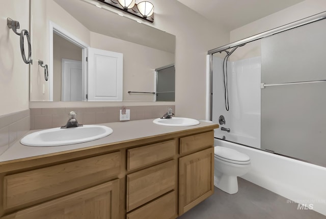 bathroom with double vanity, combined bath / shower with glass door, toilet, and decorative backsplash