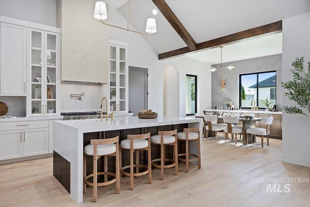 1948 Red Rock Way, Twin Falls, ID 83301 - kitchen featuring light wood-style flooring, glass insert cabinets, a center island with sink, white cabinetry, and high vaulted ceiling