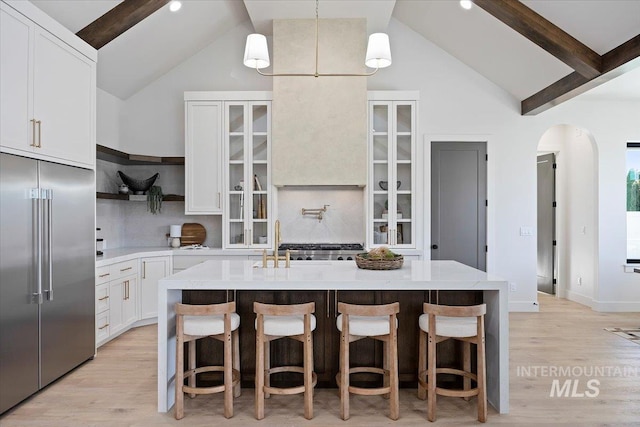 1948 Red Rock Way, Twin Falls, ID 83301 - kitchen with stainless steel built in refrigerator, arched walkways, an island with sink, backsplash, and light wood-style flooring