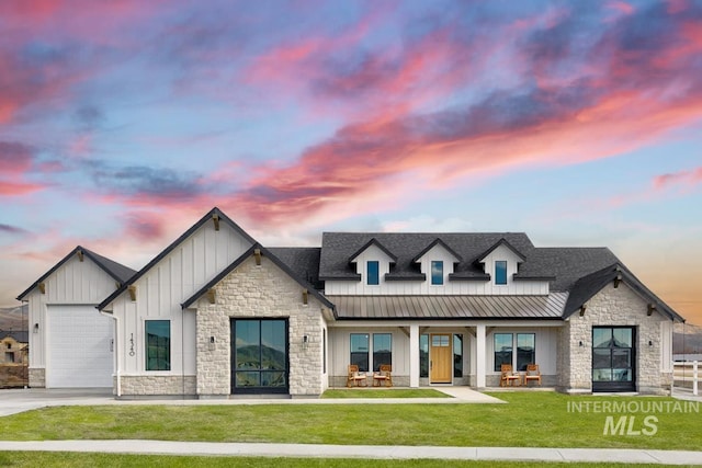 modern farmhouse style home featuring metal roof, driveway, board and batten siding, a standing seam roof, and a front yard