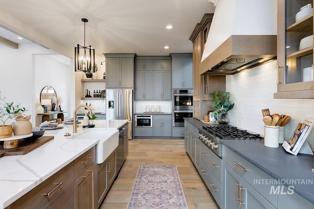 kitchen with a sink, appliances with stainless steel finishes, custom exhaust hood, open shelves, and tasteful backsplash