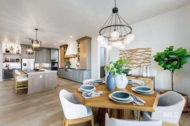 dining area with a chandelier, beverage cooler, light wood-style flooring, and recessed lighting