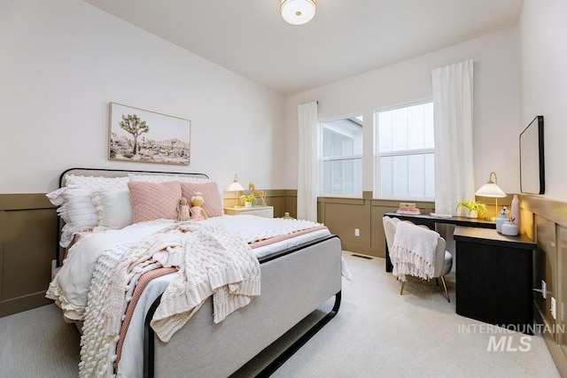 carpeted bedroom featuring visible vents and wainscoting