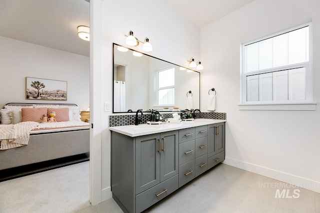 full bath with double vanity, baseboards, and a sink