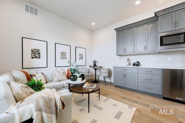 living area with recessed lighting, visible vents, and light wood-style floors