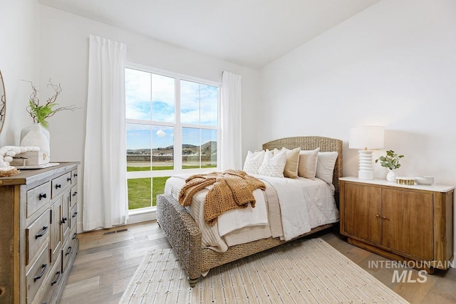 bedroom featuring lofted ceiling, light wood-type flooring, and visible vents