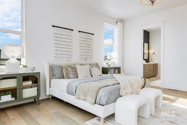 bedroom featuring baseboards, wood finished floors, and ensuite bathroom