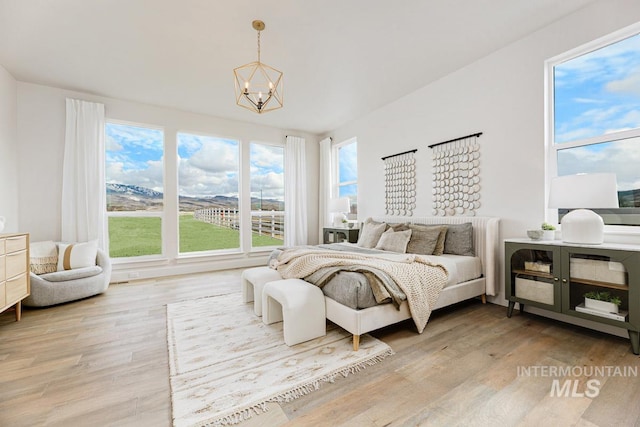 bedroom with an inviting chandelier and light wood-style flooring