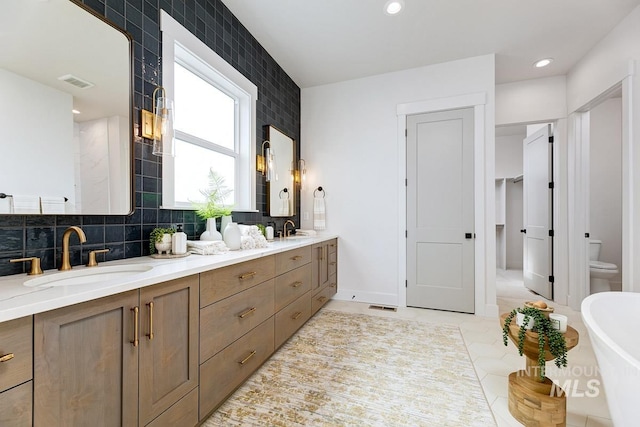 full bath featuring double vanity, visible vents, and a sink