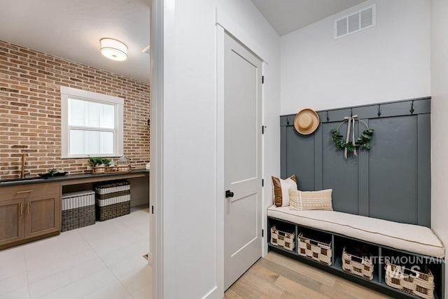 mudroom featuring visible vents, a sink, and brick wall