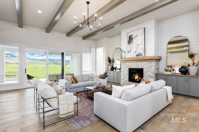 living room with an inviting chandelier, light wood-style flooring, a fireplace, and beam ceiling