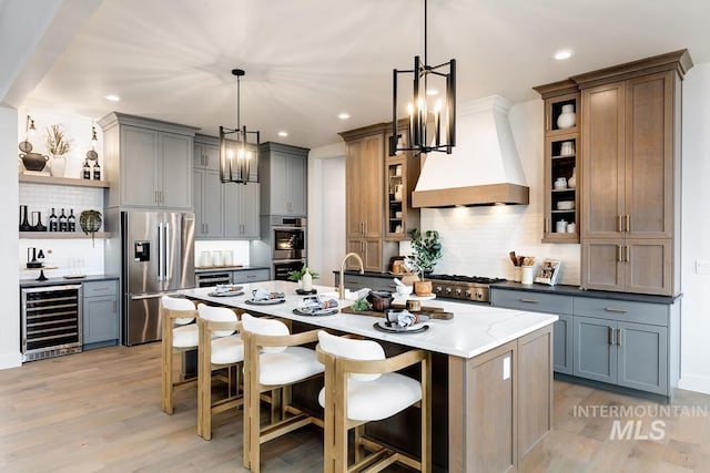 kitchen featuring appliances with stainless steel finishes, wine cooler, custom range hood, and a breakfast bar