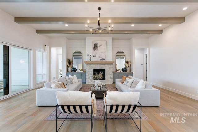 living area featuring baseboards, light wood-style flooring, an inviting chandelier, a fireplace, and beam ceiling