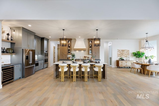 kitchen featuring wine cooler, custom exhaust hood, open shelves, an inviting chandelier, and high end refrigerator