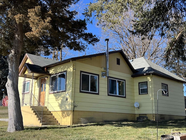 back of property featuring a shingled roof and a lawn