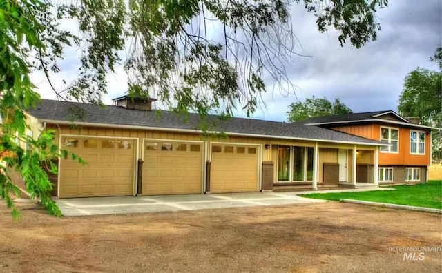 split level home with a garage, driveway, and a chimney