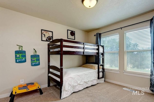 carpeted bedroom with visible vents, a textured ceiling, and baseboards