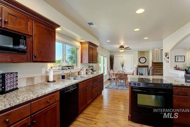 kitchen featuring a sink, visible vents, a ceiling fan, black appliances, and light wood finished floors