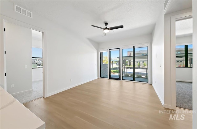 4340 E Haystack St Unit 101, Boise, ID 83716 - unfurnished room featuring wood finished floors, healthy amount of natural light, ceiling fan, baseboards, and a textured ceiling