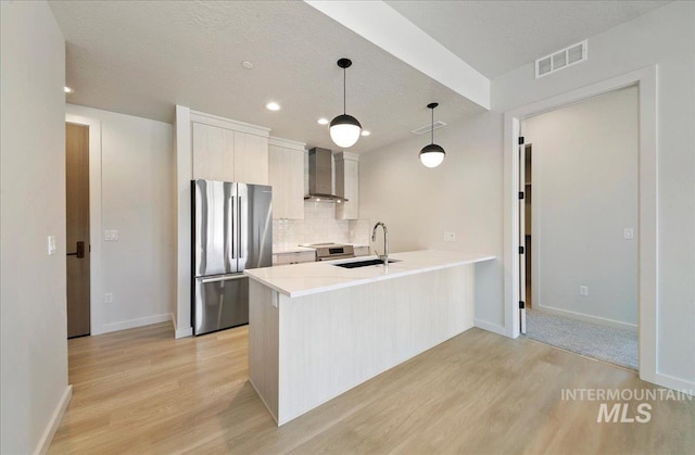 4340 E Haystack St Unit 101, Boise, ID 83716 - kitchen with stainless steel appliances, wall chimney range hood, light wood-style flooring, a sink, and a peninsula