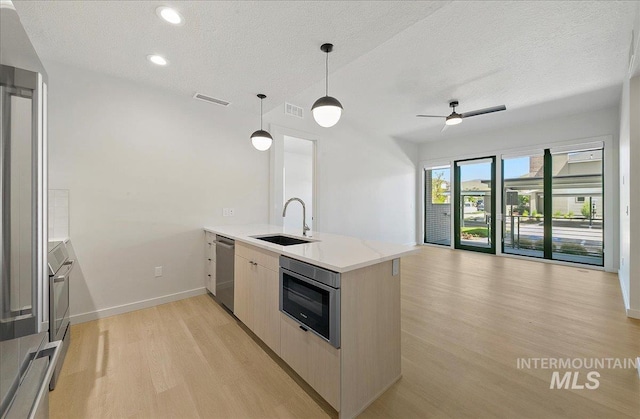 4340 E Haystack St Unit 101, Boise, ID 83716 - kitchen with appliances with stainless steel finishes, a sink, a peninsula, light wood-type flooring, and a textured ceiling